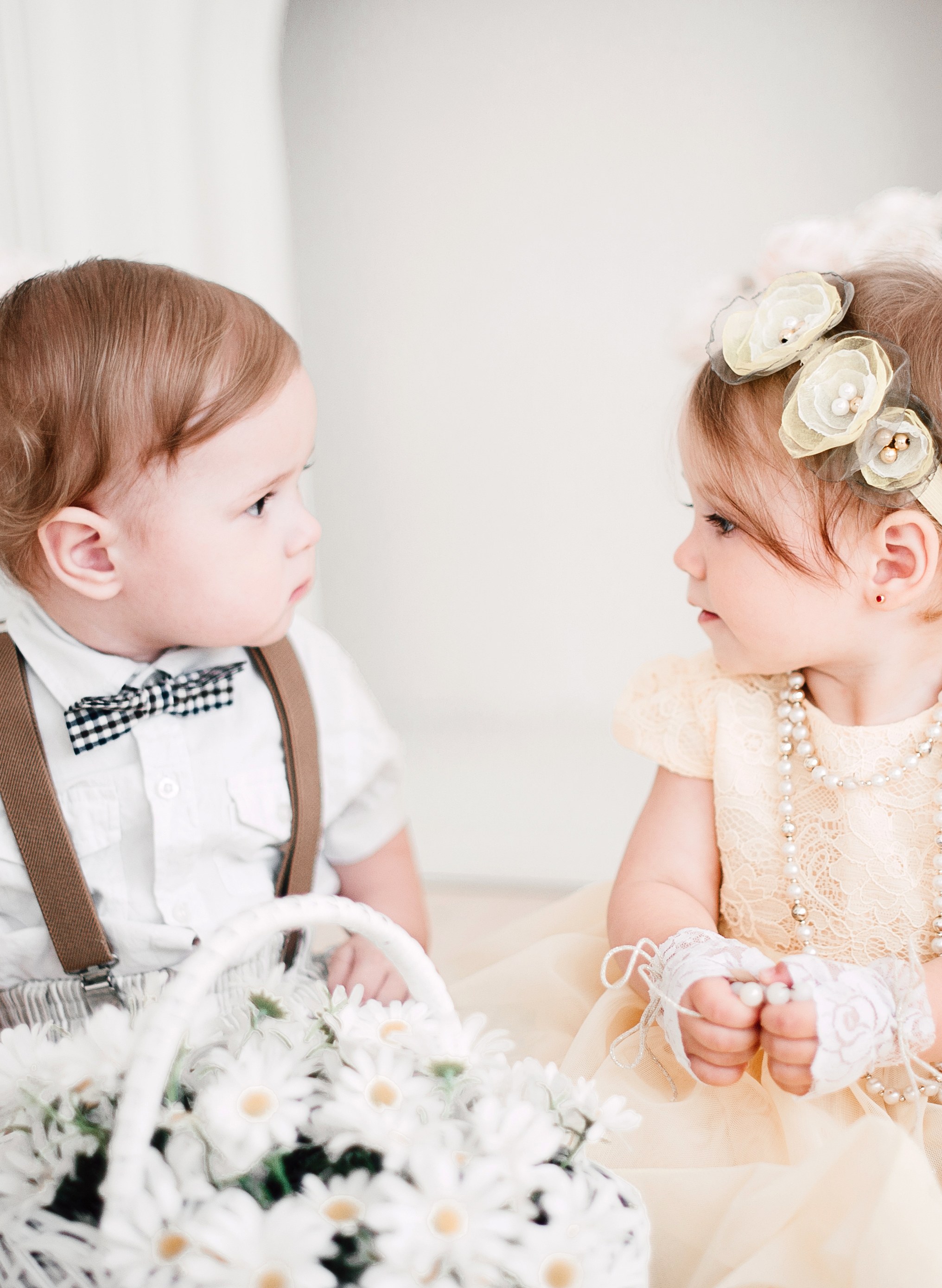 Petite fille en robe blanche de baptême, détails de la matière et de la longueur adaptés à la saison
