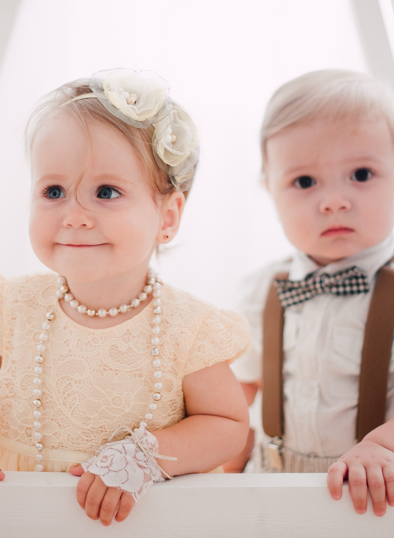 Deux jeunes enfants de face en tenue de cérémonie, dentelle crème